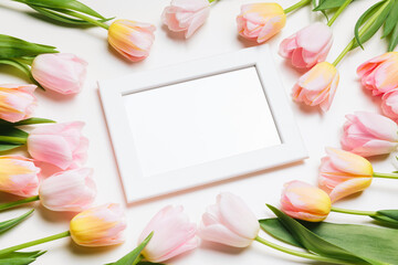 Wall Mural - Light pink and yellow blooming tulips flowers row and white picture frame over white background. Spring holiday banner, happy easter card, mothers day concept. Flat lay, top view, copy space