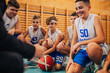 © Zamrznuti tonovi - A junior basketball team is kneeling on court with coach during training.