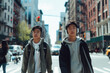 a young couple oriental teenage boy with wireless headphones listening to music is crossing a street.
