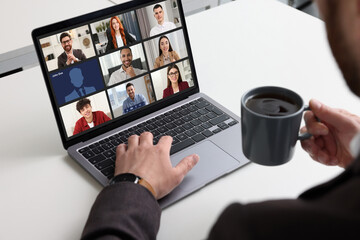 Canvas Print - Man having video chat with coworkers via laptop at white table, closeup