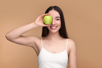 Canvas Print - Beautiful young woman with apple on beige background