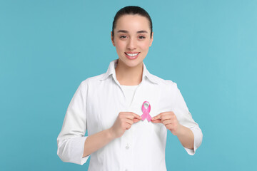 Wall Mural - Mammologist with pink ribbon on light blue background. Breast cancer awareness