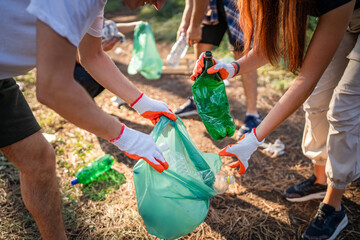 hands of unknown friends pick up waste garbage to clean forest