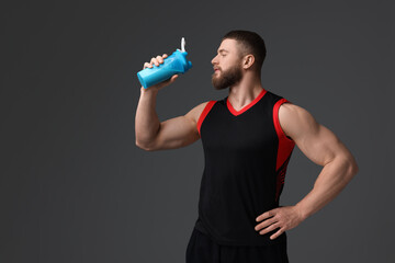 Wall Mural - Young man with muscular body holding shaker of protein on grey background, space for text