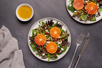 Wall Mural - Food photography of salad with bloody orange, leaf mix, spinach, red lettuce, rocket, feta cheese, caramelized pecan, nut, sauce, vegetarian