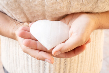 Wall Mural - Womans hands holding heart made of stone crystal with flower of life pattern