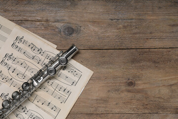 Canvas Print - Sheets with musical notes and flute on wooden table, flat lay. Space for text