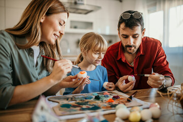 Parents and child engaged in a fun egg-painting session at the dining room