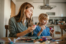 Heartwarming scene of a mother and daughter joyfully decorating Easter eggs together