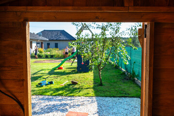 Wall Mural - A wooden garden shed standing on a concrete foundation in a garden, view from inside the house.