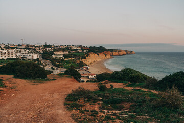 Wall Mural - Picturesque sunset over cliffs and the ocean, with the silhouette of a city adding a touch of urban charm to the breathtaking natural landscape. Lagos, Portugal