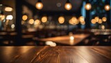Fototapeta Pokój dzieciecy - Empty wooden table top with a background of blurred golden bokeh in a dimly lit cafe restaurant
