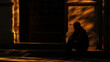A man sitting on a stoop the shadows of ping cars intermittently covering him in darkness.