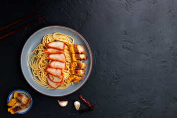 Sticker - Red pork noodles with barbecue pork, crispy pork, dumplings, green vegetables, healthy food, Thai, Chinese, Hong Kong, arranged on a black table. Top view with text copy space.