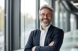 © Adriana - Smiling confident mature businessman looking at camera standing in office. Elegant stylish corporate leader successful ceo executive manager wearing glasses