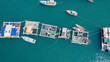 Aerial view of a traditional fish farm with floating structures and boats in tropical blue waters