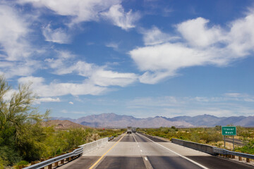 Beautiful blue sky with fluffy clouds over the highway on a spring day. Arizona sign. Scenic road in Arizona, USA on a sunny summer day. Arizona, USA - 17 April 2020