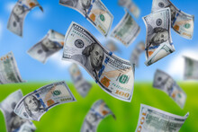 Flying Dollars Banknotes On The Background Blue Sky And Green Grass. Money Is Flying In The Air. 100 US Banknotes New Sample.