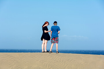 Two teenagers stand on a sand dune