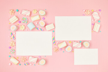 Set of three blank white cards on cute pastel pink kawaii background with frame of sweet candies, meringue and marshmallows . Flat lay, top view, copy space. Beautiful childlike design template