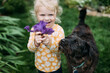 Young girl holding purple iris flower smiling with pet dog