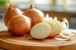 © Straxer - Front view of a sliced golden onion on a wooden cutting board with a defocused kitchen background.