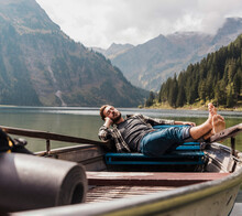 Young Man Relaxing In Boat At Lake Vilsalpsee Near Mountains, Tyrol, Austria