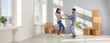 © Studio Romantic - Happy young couple celebrating moving day with cardboard boxes in background smiling and dancing with in new appartment. Family having fun. Relocating, real estate, mortgage concept. Banner.