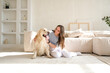 © lelechka - Portrait of happy young woman with pet dog, sitting on floor at home. Caucasian female hugging golden retriever in living room