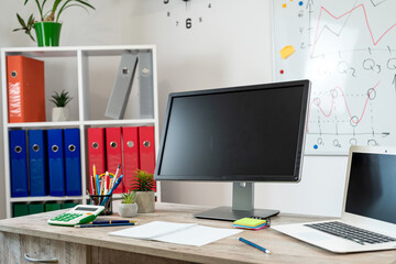 Poster -  wooden table with laptop pc monitor pen andd other, whiteboard with business graph on wall