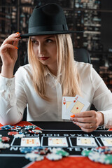 Pretty woman holding two aces and play poker at casino table