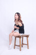 full body beautiful asian woman 20s formal office elegant sexy sitting sensual hands holding strap top pliers on wooden chair isolated white background