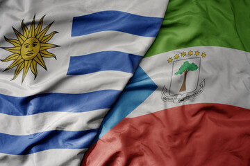 Wall Mural - big waving national colorful flag of equatorial guinea and national flag of uruguay .