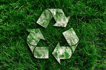 recycling sign with green grass and leaves