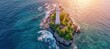 Aerial view of lonely lighthouse on island hit by ocean waves at dusk on sunny golden hour day