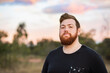 © Austockphoto - Portrait of a young aussie man with beard, outside at dusk wearing black t-shirt