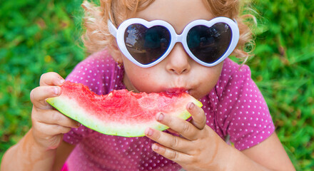 Poster - Child girl in the park eats watermelon. Selective focus.