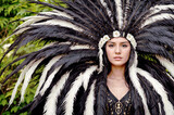 Fototapeta Tulipany - A woman with long black hair and a large feathered headdress.