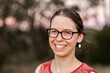 © Austockphoto - Happy young adult with glasses smiling outside - youth portrait