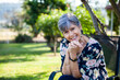 © Austockphoto - Woman sitting on a chair in garden laughing