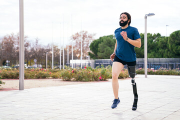 Cheerful bearded runner with advanced carbon fiber prosthetic leg enjoying a run in a scenic park with a cloudy sky backdrop