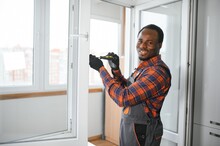 Workman In Overalls Installing Or Adjusting Plastic Windows In The Living Room At Home