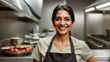 Confident Indian woman with a bright smile wearing a chef's apron in a professional kitchen, representing culinary expertise and passion.