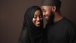 Portrait of loving african american young muslim couple posing on grey studio background. Beautiful black man and woman in hijab hugging and smiling at camera, relationships concept 