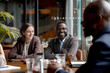 © ADDICTIVE STOCK - Group of People Sitting Around a Wooden Table at a Business Meeting