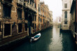 Small waterways of Venice. River canal with old brick medieval buildings in foggy day, Italy. Typical boat transportation. Venetian travel urban scene. Water transport. Popular tourist destination.