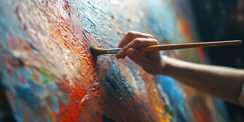 Aufkleber - A person is seen holding a paintbrush and diligently painting on a canvas. This image can be used to depict creativity, artistry, and the process of painting