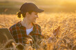 © scharfsinn86 - Woman farmer working with laptop on wheat field. Smart farming and digital agriculture..