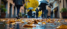 Blur Obscures Faces As People Walk By With Rain Gear And Leaves Litter The Wet Sidewalk Of A Udine Alley On A Rainy Autumn Day.