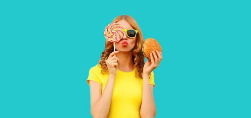 Wall Mural - Portrait of happy cheerful young woman with burger fast food and sweet lollipop